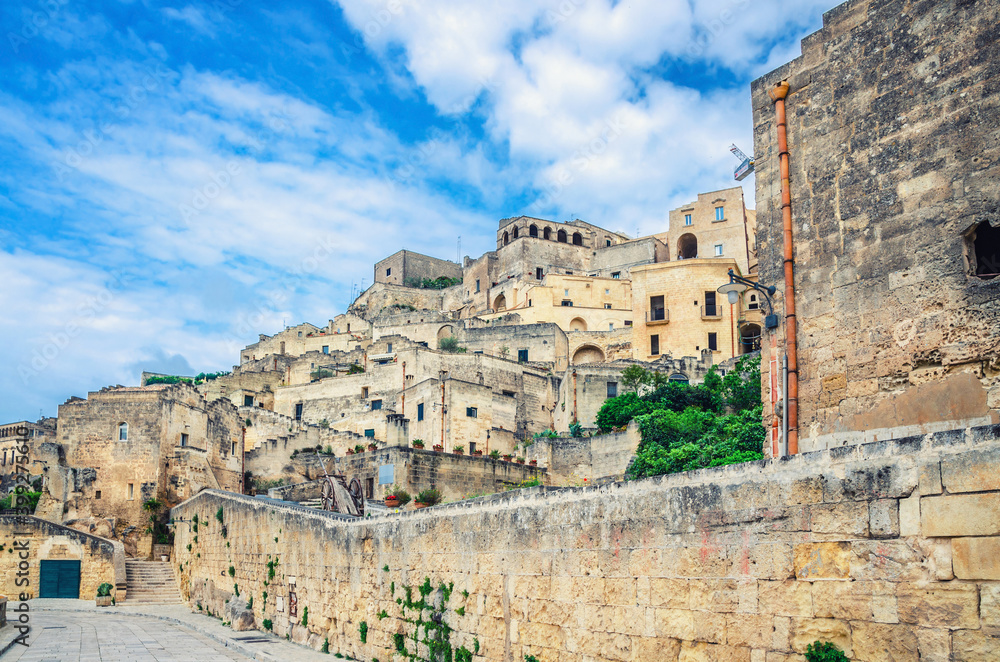 Stone streets and buildings in Matera town historical centre Sasso Caveoso of old ancient town Sassi di Matera, blue sky white clouds, UNESCO World Heritage Site, Basilicata, Southern Italy