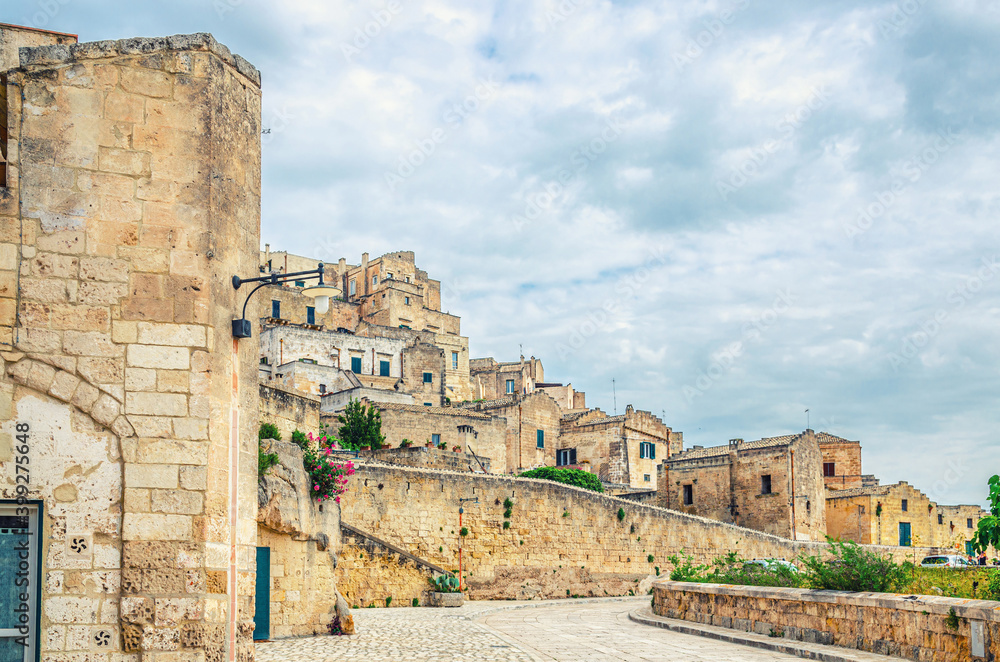 Stone streets and buildings in Matera town historical centre Sasso Caveoso of old ancient town Sassi di Matera, blue sky white clouds, UNESCO World Heritage Site, Basilicata, Southern Italy