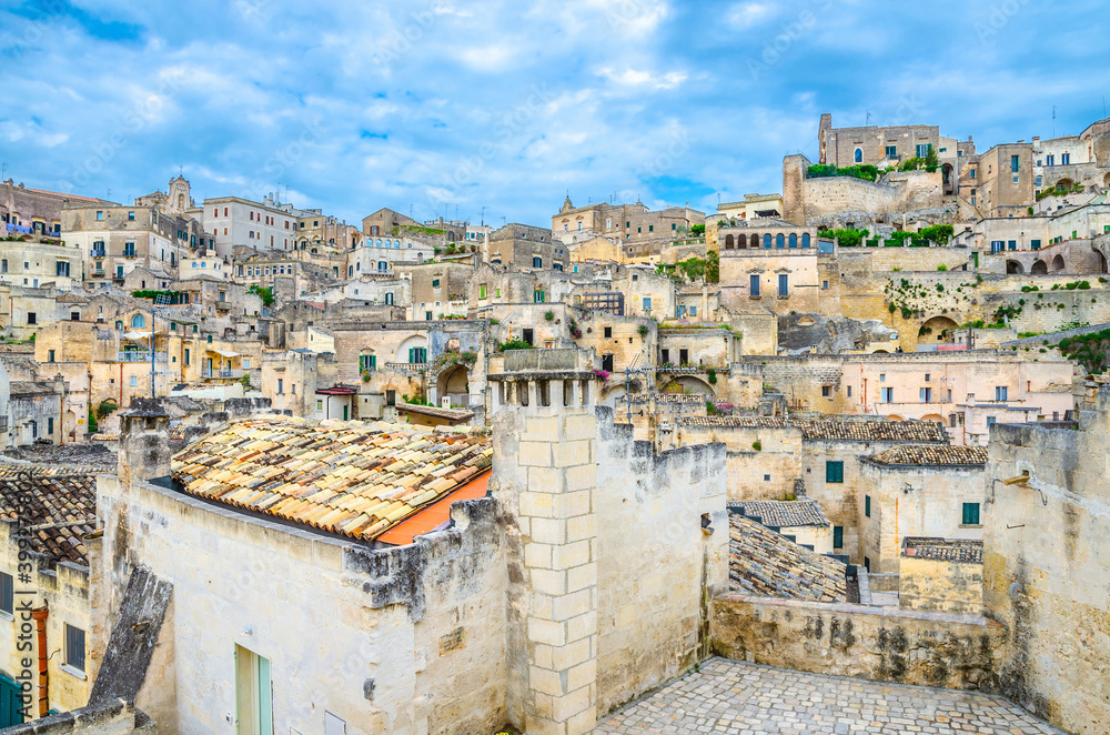 Fototapeta premium Sassi di Matera, historical centre Sasso Caveoso of old ancient town with rock cave houses, blue sky and white clouds, UNESCO World Heritage, Basilicata, Southern Italy