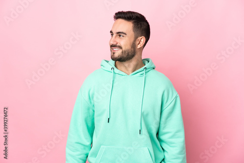 Young caucasian handsome man isolated on pink background looking to the side and smiling © luismolinero