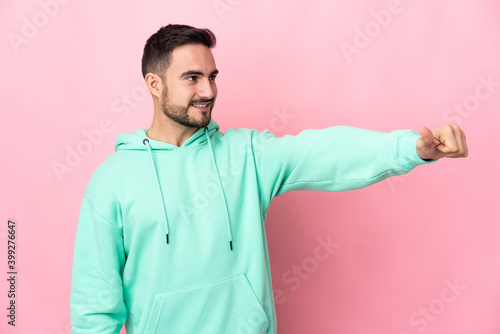 Young caucasian handsome man isolated on pink background giving a thumbs up gesture © luismolinero