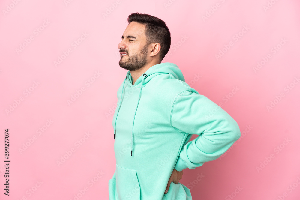 Young caucasian handsome man isolated on pink background suffering from backache for having made an effort Young caucasian handsome man isolated on pink background suffering from backache for having made an effort