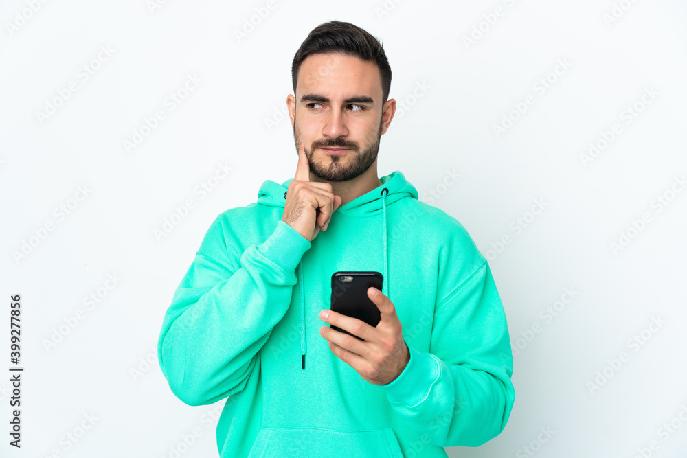 Young caucasian handsome man isolated on white background using mobile phone and thinking Young caucasian handsome man isolated on white background using mobile phone and thinking