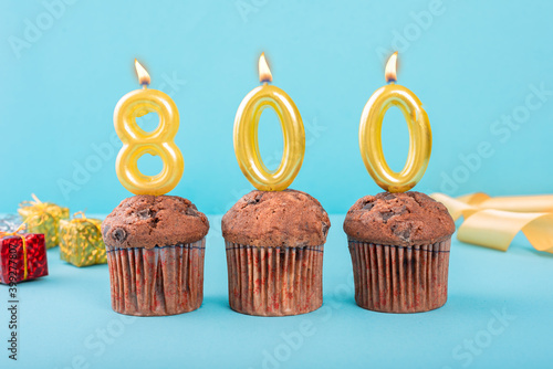 800 Number gold candle on a cupcake against a pastel blue background eight hundred year celebration