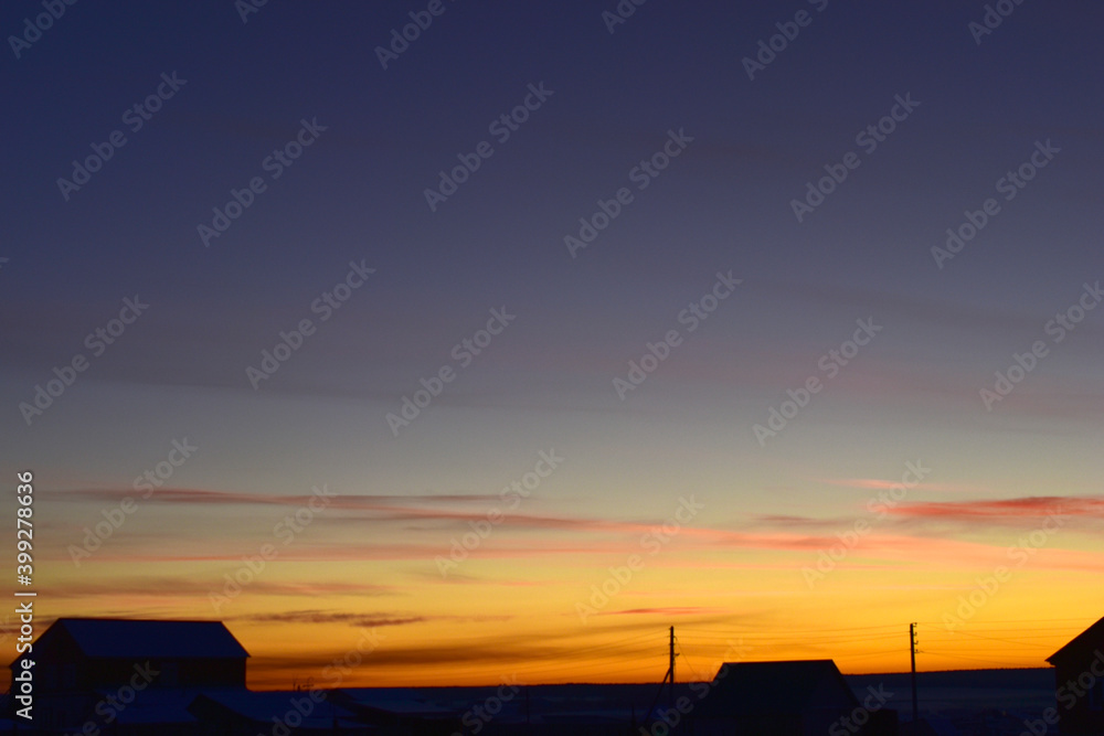 Lilac yellow sunset sky in the village in winter Lilac yellow sunset sky in the village in winter