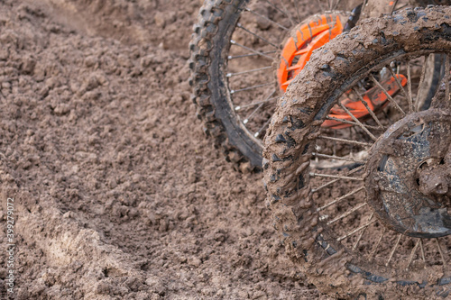 Two muddy front wheels of enduro motorcycles covered with sand with copy space on the left