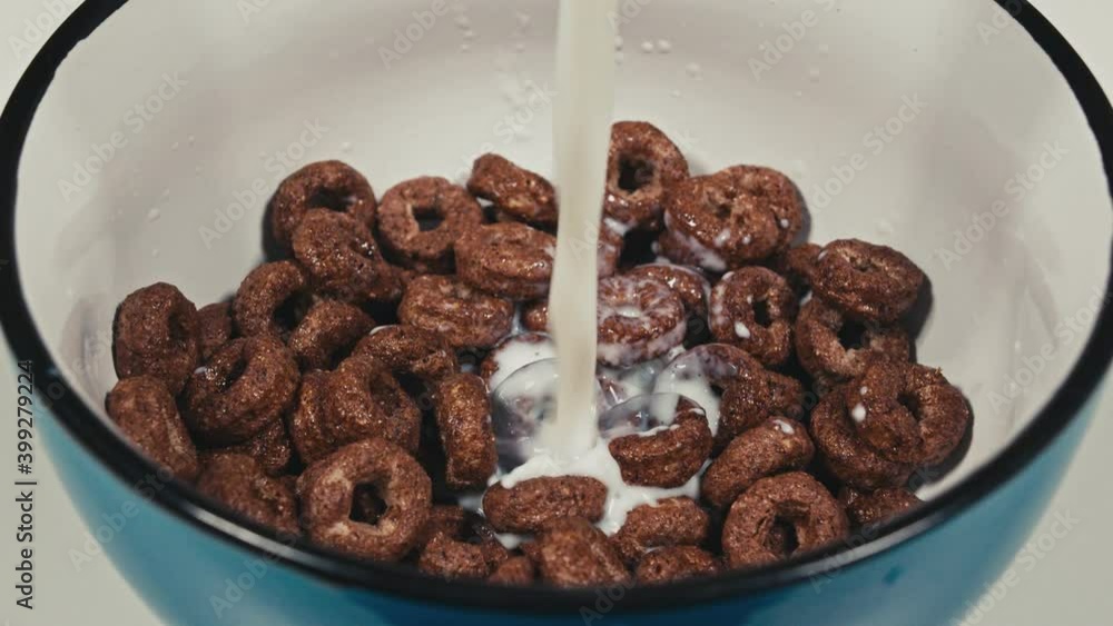 Milk being poured over breakfast cereal hoops. Top view