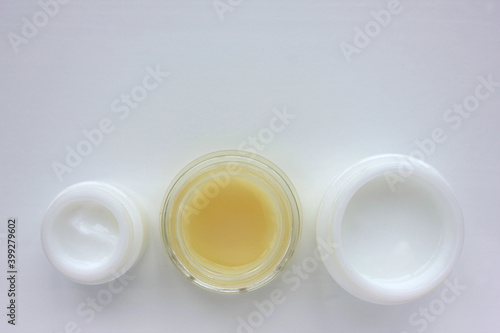 Facial cream on white background. Flat lay composition with variety of face cream in glass jars. Copy space