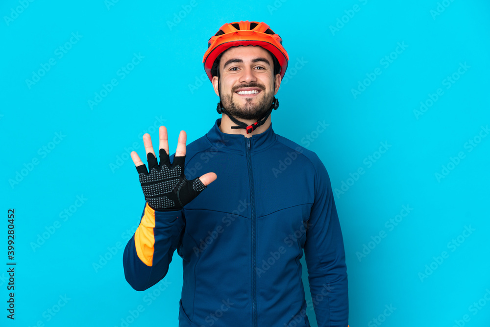 Young cyclist man isolated on blue background counting five with fingers