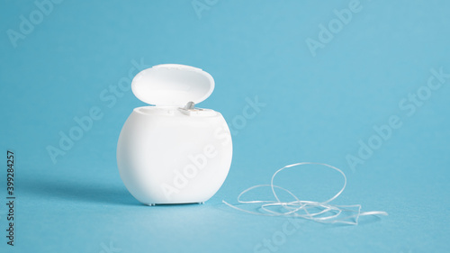 Dental floss and white case on a blue background. Copy space. Dental care. Interdental thread and box. Flossing tool