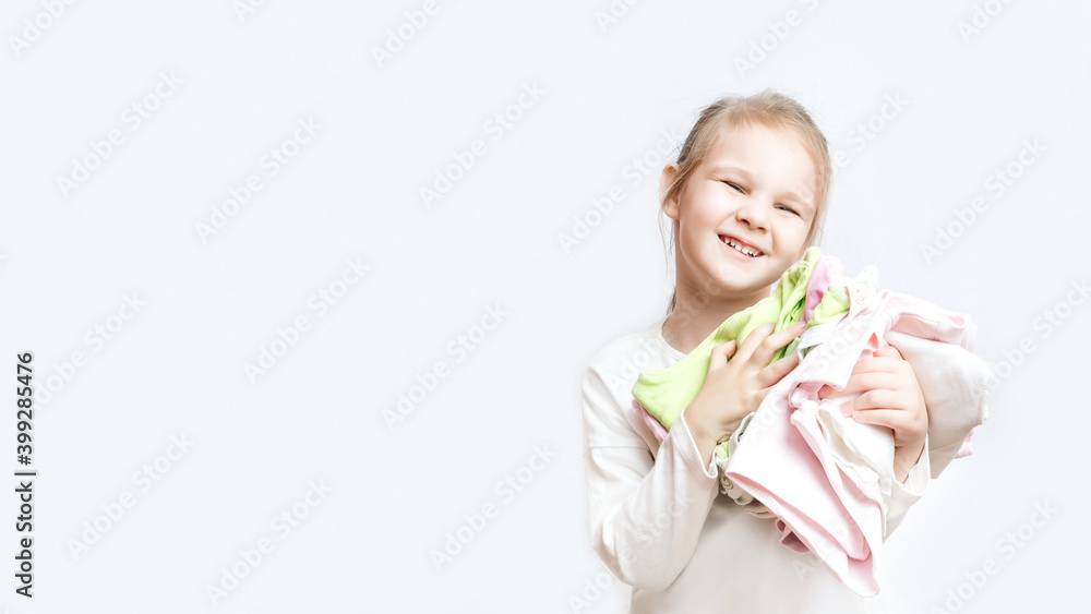 Smiling cute little caucasian girl is leaning on the ironing board at home. Daughter helps mom iron baby clothes. White background. childhood concept Smiling cute little caucasian girl is leaning on the ironing board at home. Daughter helps mom iron baby clothes. White background. childhood concept