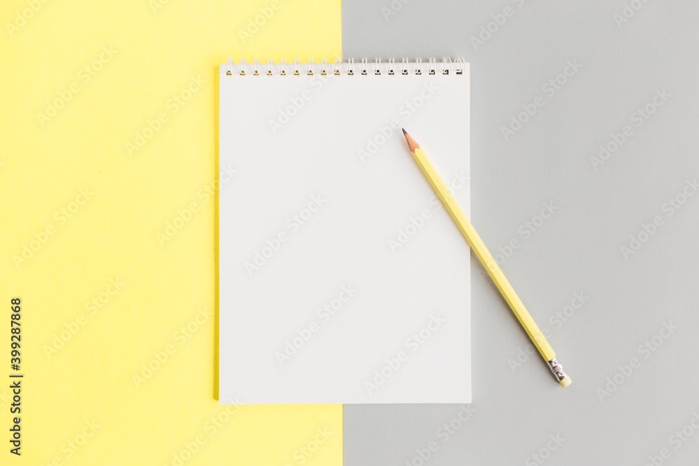 Notebook with blank page and pencil on a grey and yellow background. Notebook with blank page and pencil on a grey and yellow background.