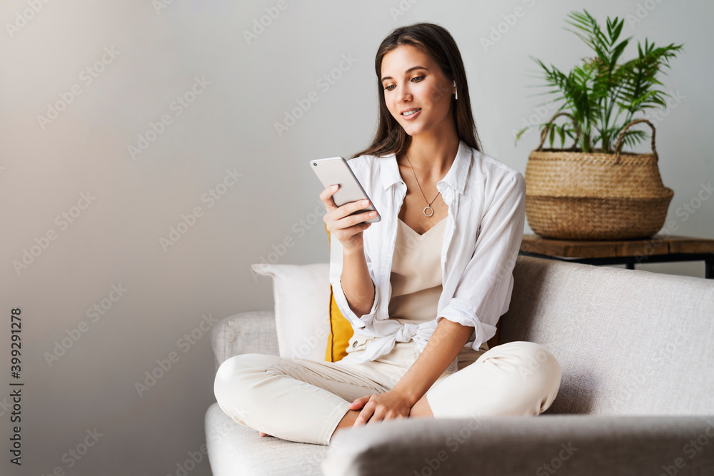 Female relaxing at home, using smartphone to text messages, share photos, communicate with friends, check email, watch videos, play games online. Entertainment opportunities on web connected gadgets. Female relaxing at home, using smartphone to text messages, share photos, communicate with friends, check email, watch videos, play games online. Entertainment opportunities on web connected gadgets.