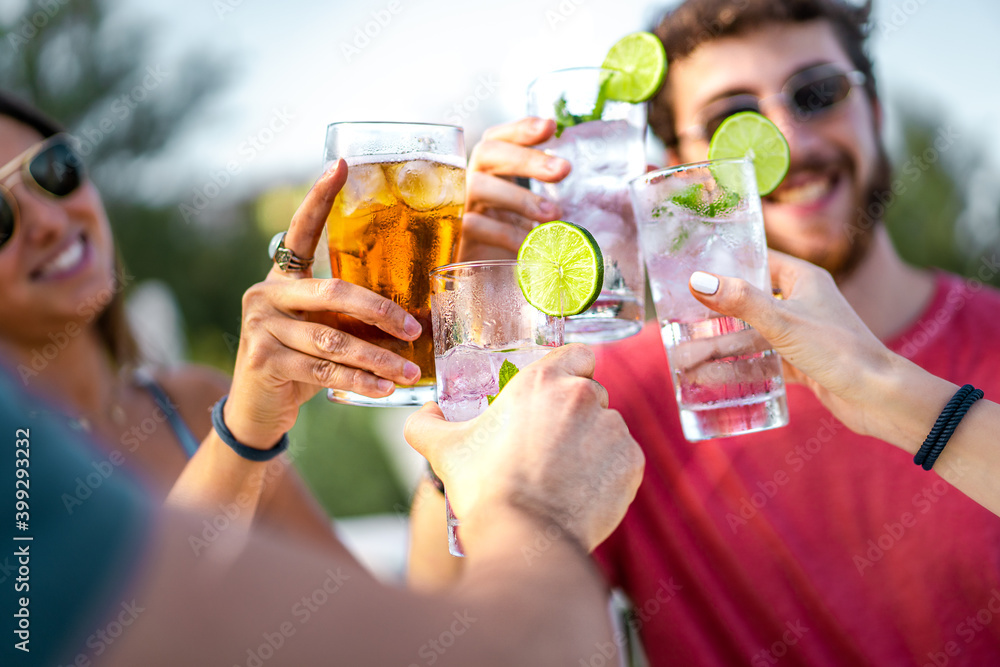 Happy young friends toasting with mojito cocktails together. Focus on the glasses clinking. Friendship and alcohol abuse concept. Happy young friends toasting with mojito cocktails together. Focus on the glasses clinking. Friendship and alcohol abuse concept.