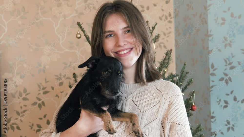 Pretty young Female owner is hugging, petting, stroking, kissing her lovely cute black dog. Funny cute face. Christmas time. Funny Christmas dog concept Pretty young Female owner is hugging, petting, stroking, kissing her lovely cute black dog. Funny cute face. Christmas time. Funny Christmas dog concept
