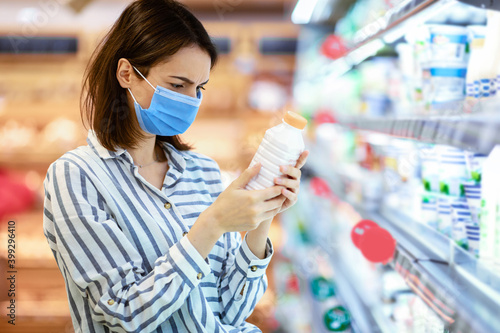 Woman in medical mask shopping groceries, buying milk