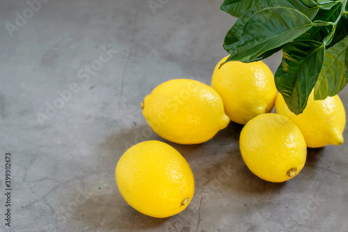 Fresh yellow limons on the grey textured background close up. Top view, copy space. Fresh fruit for healthy eating.