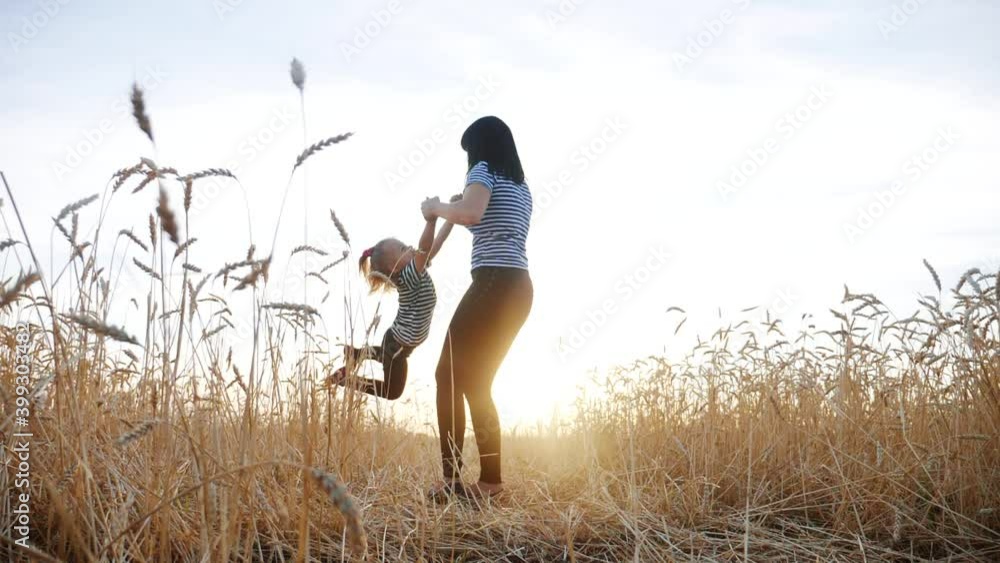 mom play with her daughter the park in wheat field. happy family people in the park concept. mom play is spinning daughter holding hands in wheat field. childhood dream happy fun family mom play with her daughter the park in wheat field. happy family people in the park concept. mom play is spinning daughter holding hands in wheat field. childhood dream happy fun family