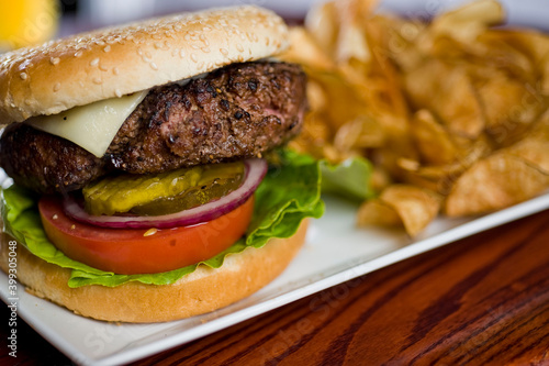 Hamburger. Cheeseburger. Classic traditional American bar, restaurant or pub menu item. Beef hamburger with Swiss and cheddar cheeses served with lettuce, tomato, onion and hand cut french fries. 