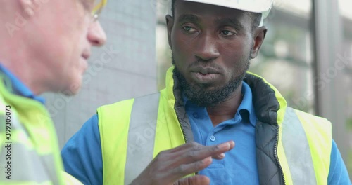 Diversity team senior industry engineer discuss for report and strategy plan in safety uniform and helmet at factory manufacturing. Maintenance worker meeting outdoor on building background