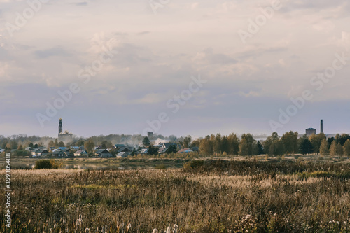autumn evening landscape with a field and a river and a Christian Church on the horizon © alexkoral
