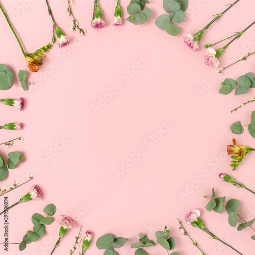 Wreath made of flowers and eucalyptus on a pink pastel background. Floral frame with copy space.