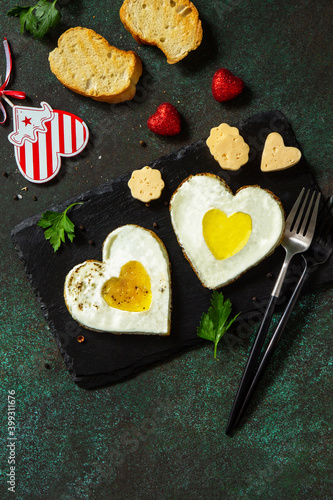 Breakfast on Valentines Day or brunch. Heart shape fried egg on slate plate. Top view flat lay. Copy space.