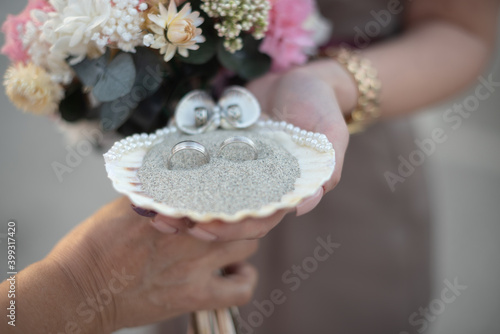 wedding rings inside a shell with sand