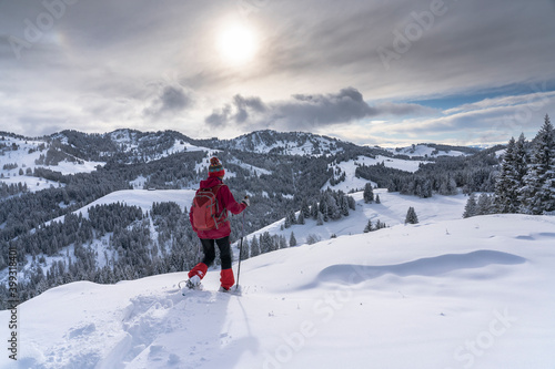 nice and active senior woman snowshoeing in deep powder snow in the Allgau alps, Bavaria, Germany