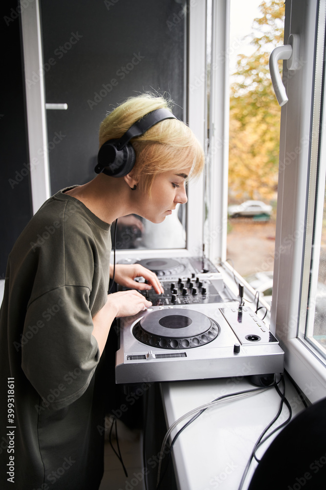 Obraz premium Woman wearing headphones looking at the dj console