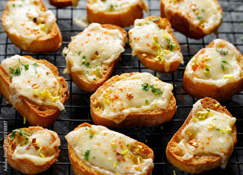 Konstfotografi Cheese  crostini  sprinkled with spices and chopped fresh herbs, close up view
