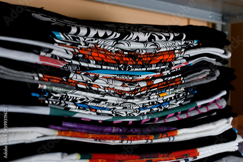 selective focus photo of t-shirts with bright prints, printed by silkscreen. serigraphy production. printing images on t-shirts in a design studio.