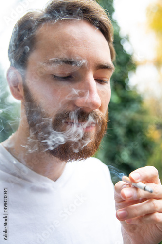 Young adult man smoking a cigarette. Nicotine addiction.