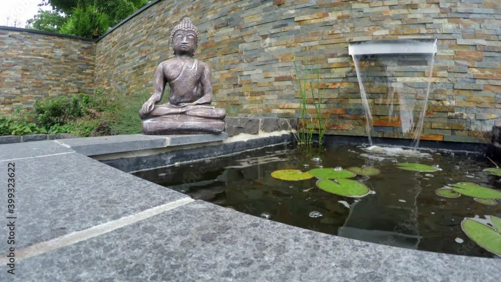 Buddha Figur an einem Gartenteich mit Wasserfall als Mediation