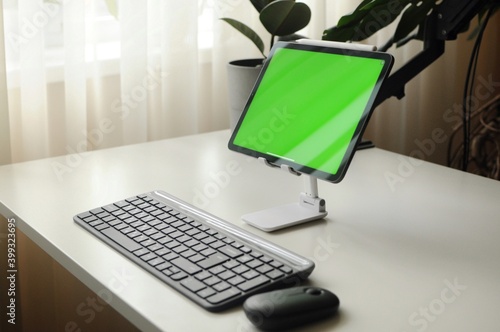 Tablet on stand with keyboard and mouse. Minimalism interior with homeplants photo