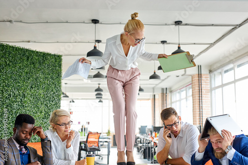 rude angry female boss executive is dissatisfied irritated by employees, scream at them, incompetent workers. in modern office