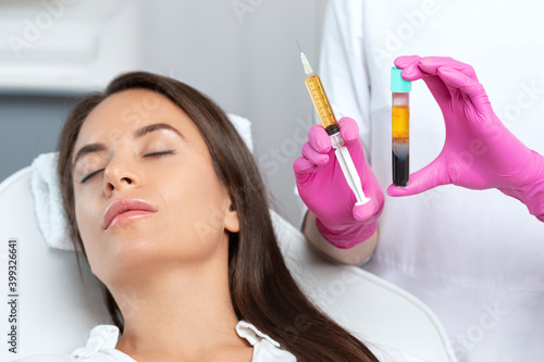 Beautician will do PRP therapy for the face against wrinkles. She has blood plasma for injections and a syringe with plasma in her test tube. Cosmetology in the beauty salon. photo