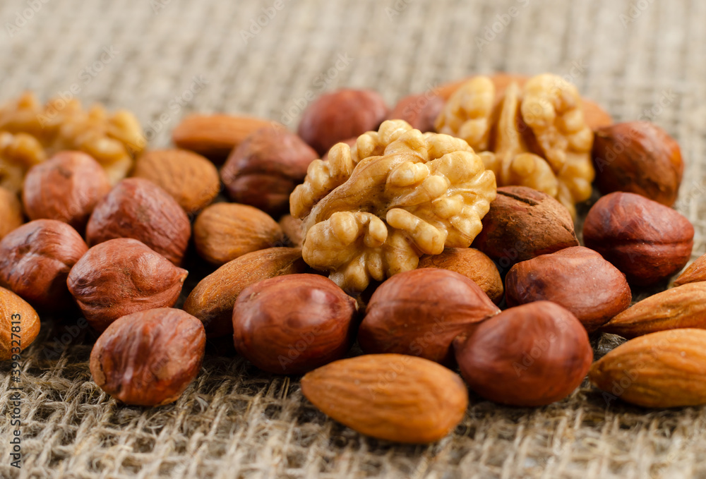 Hazelnuts, walnuts, and almonds lie on a factory-made sackcloth. Nuts are a high-calorie and healthy product. Hazelnuts, walnuts, and almonds lie on a factory-made sackcloth. Nuts are a high-calorie and healthy product.