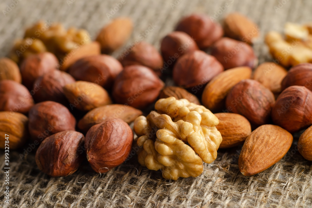 Hazelnuts, walnuts, and almonds lie on a factory-made sackcloth. Nuts are a high-calorie and healthy product. Hazelnuts, walnuts, and almonds lie on a factory-made sackcloth. Nuts are a high-calorie and healthy product.