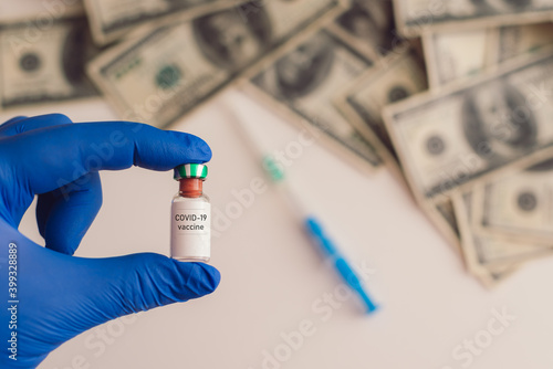 covid-19 vaccine in hand with money in the background