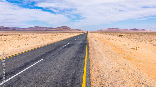 A tarmac highway cuts through the dry, arid landscape of the Namib Desert near Aus, Namibia.