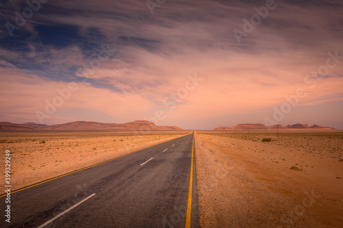 A tarmac highway cuts through the dry, arid landscape of the Namib Desert near Aus, Namibia.