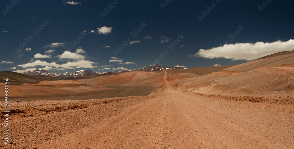 The dirt road high in the Andes mountains. Traveling along the route across the arid desert and mountain range. The sand and death valley under a deep blue sky in La Rioja, Argentina. 