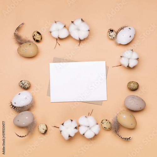 Craft Easter eggs and empty envelope on beige pastel background, space for text. Flat lay image composition, top view.