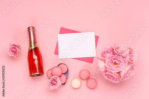 Flowers roses, envelope and sweets macaroons on pink background. Valentines day concept. Flat lay, top view, copy space.