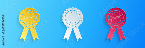 Paper cut Approved or certified medal badge with ribbons icon isolated on blue background. Approved seal stamp sign. Paper art style. Vector.