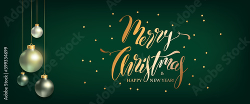 Merry Christmas Lettering greeting banner. Xmas Balls hanging on green background with gold confetti. Elegant Winter Holidays Design