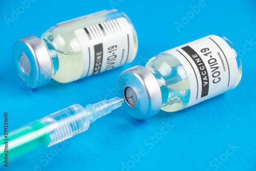 Syringe and vaccine COVID-19. Coronavirus on blue background