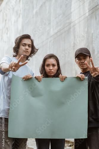 Portrait students holding blank paper who are burning with enthusiasm doing a demonstration together photo