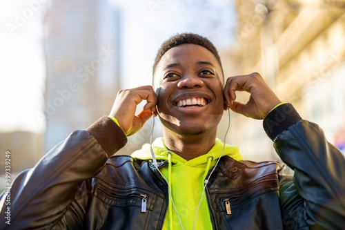 Young man wearing headphones and listening to music in the city
